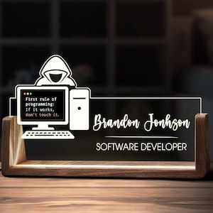 Könnte beinhalten: Personalisiertes Namensschild für einen Softwareentwickler. Das Design zeigt eine Computergrafik mit dem Text "First rule of programming: If it works, don't touch it." Der Name "Brandon Jonhson" und der Titel "SOFTWARE DEVELOPER" sind ebenfalls zu sehen.