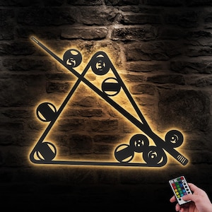 Può includere: Arte da parete in metallo nero che rappresenta un triangolo da biliardo con stecche e palle da biliardo. L'opera d'arte è illuminata da luci LED bianco caldo e include un telecomando per cambiare il colore delle luci.