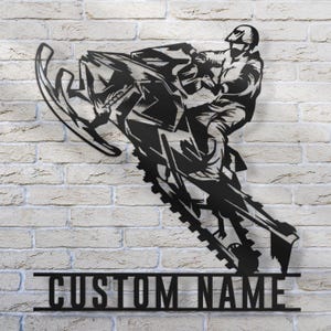 Puede incluir: Silueta negra de metal de una persona conduciendo una moto de nieve, con las palabras "CUSTOM NAME" debajo.