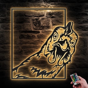 Puede incluir: Una decoración de pared de metal negro con la cabeza de un gallo con el pico abierto. El gallo está iluminado con luz blanca cálida y está colocado contra una pared de ladrillo. Un mando a distancia con luces de cambio de color se muestra en la esquina inferior derecha de la imagen.