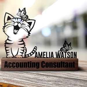 May include: A black and white silhouette of a cat with a butterfly on its head, sitting on a wooden desk plaque. The plaque reads "Amelia Watson Accounting Consultant".