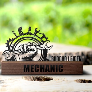 Puede incluir: Placa de metal negro con un diseño de llave inglesa y otras herramientas. La placa tiene las palabras "BUDDHO LEIDEN" y "MECHANIC" en ella.