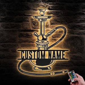 May include: A black metal silhouette of a hookah with a hose and a custom nameplate. The silhouette is illuminated with warm white light. A remote control with multiple color options is shown in the bottom right corner.