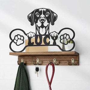 May include: A black metal dog-themed wall shelf with hooks. The shelf features a dog silhouette above a bone-shaped design with the name "LUCY". Below the shelf are four hooks, with a green towel, keys, and a red leash hanging.