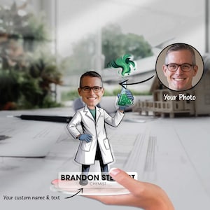 Könnte beinhalten: Eine personalisierte Acrylfigur eines Chemikers, der einen mit grüner Flüssigkeit gefüllten Kolben mit grünem Dampf hält. Die Figur trägt einen weißen Laborkittel, eine Brille und blaue Handschuhe. Die Basis trägt den Namen "BRANDON STEWART" und das Wort "CHEMIST". Ein Foto befindet sich oben rechts.