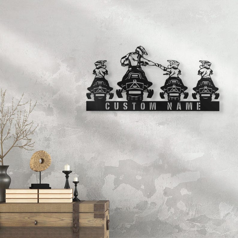 May include: Black metal wall art featuring four snowmobile riders, with the text "CUSTOM NAME" below.