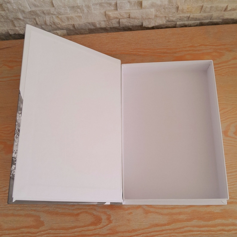 May include: An open white cardboard box with a black and white patterned design on the front. The box is empty.