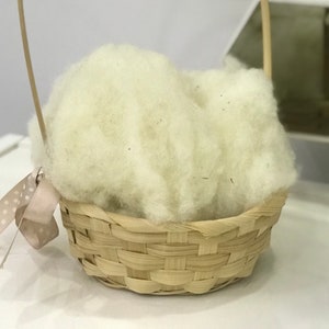 May include: A small, woven basket with a handle, filled with white cotton batting.