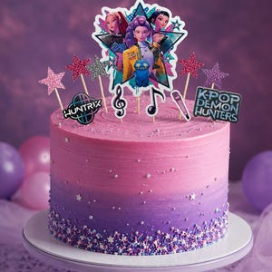 Peut inclure: Un gâteau rond avec un glaçage dégradé rose et violet, décoré de perles en sucre blanches et de confettis en forme d'étoiles. Les décorations incluent trois personnages, une créature bleue, des notes de musique, un micro et les inscriptions HUNTRIX et KPOP DEMON HUNTERS.