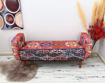 May include: A red, blue, and cream patterned bench with wooden legs. The bench is upholstered in a traditional Turkish kilim style fabric.