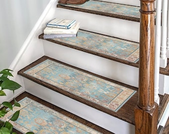 May include: A set of blue and beige patterned stair treads with a decorative border. The treads are placed on a wooden staircase with a white railing.