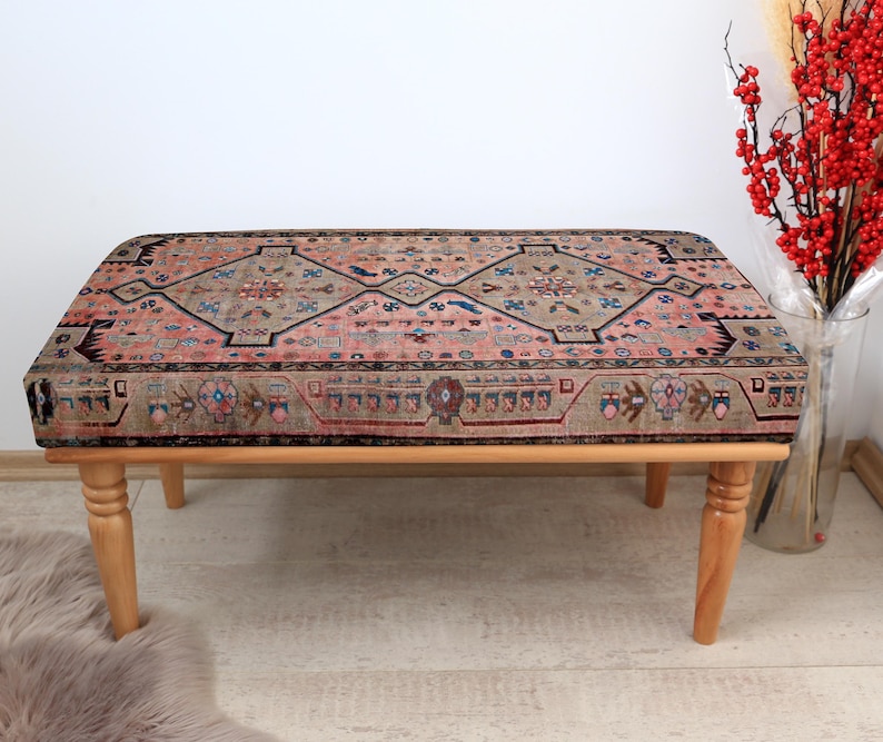 May include: A wooden bench with a colorful patterned cushion. The cushion has a traditional design with shades of pink, blue, and brown.