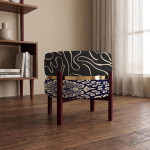 May include: A round stool with a dark brown wooden frame and four legs. The upper section features a black fabric with a beige abstract line pattern, separated by a gold metal band from the lower section, which has a blue and white floral pattern.