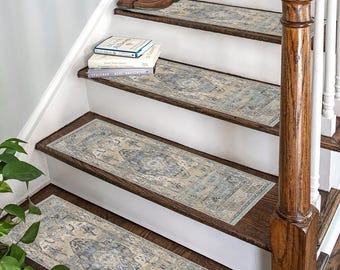 May include: A set of non-slip stair treads with a blue and beige patterned design. The treads are placed on a wooden staircase with a white railing.