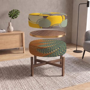 May include: A multi-tiered furniture piece featuring a top circular cushion with a yellow, gray, and sage green abstract pattern, a middle circular wooden tray with a gold rim, and a bottom circular cushion with a teal and orange scale pattern.
