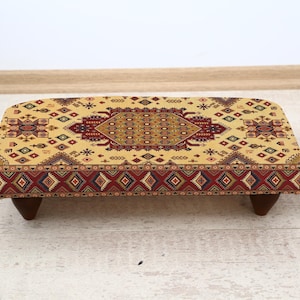Klassieke geelkleurige voetenbank met traditionele patronen, voetenbank naast het nachtkastje met houten poten, elegant accent voor een gezellig interieur