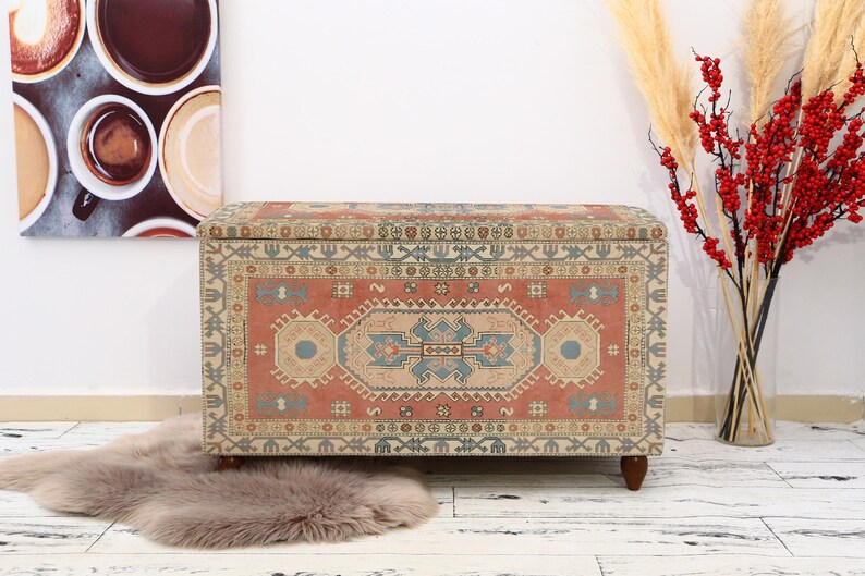 May include: A decorative storage chest with a colorful rug pattern. The chest is made of wood and has a rectangular shape. The chest is sitting on a white floor.