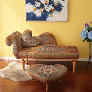 May include: A decorative chaise lounge and heart-shaped ottoman set with a patterned fabric in shades of orange, blue, and green. The furniture sits on wooden legs. A faux fur rug and a vase of blue flowers are nearby.