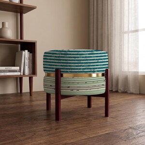 May include: A round ottoman featuring a two-tone striped fabric design with teal and white horizontal stripes on the top half and light green and white stripes on the bottom half, separated by a gold metal band and supported by dark wood legs.
