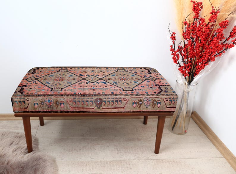 May include: A wooden bench with a colorful patterned cushion. The cushion has a geometric design with shades of pink, blue, and brown.