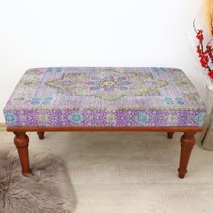 May include: A wooden bench with a purple and blue patterned cushion. The cushion has a floral design with a central medallion.
