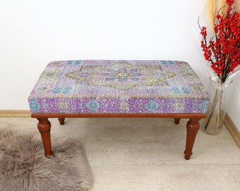 May include: A wooden bench with a purple and blue patterned cushion. The cushion has a floral design with a central medallion.
