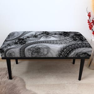 Op de afbeelding: Een rechthoekige bank met een zwart metalen frame en vier poten. De zitting heeft een zwart-wit abstract patroon. De bank staat voor een witte muur. Afmetingen: ongeveer 120 cm lang.