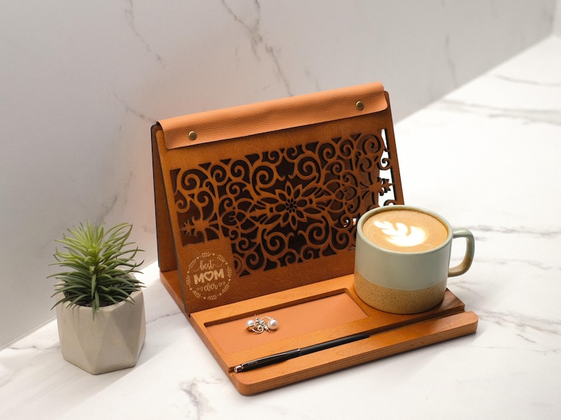 May include: A wooden stand with a leather-covered top and a cutout design. The stand has a small tray for holding a cup of coffee or tea. The stand is engraved with the words "Best Mom Ever".