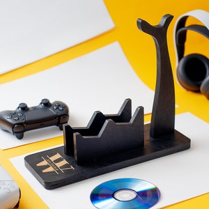 May include: A black wooden stand with a headset holder, two slots for controllers, and a space for a disc. The stand has the text "WWW" on the front. A white headset, a black controller, and a blue disc are on the stand.