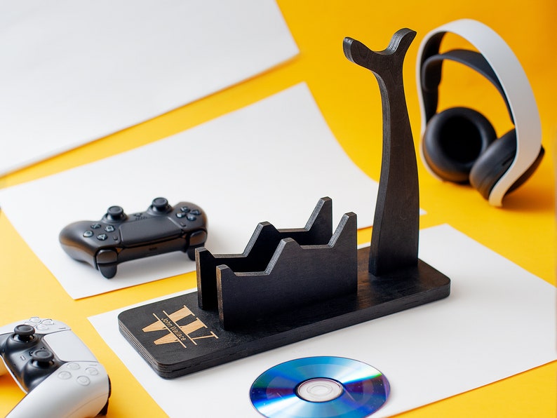 May include: A black wooden stand with a headset holder, two slots for controllers, and a space for a disc. The stand has the text "WWW" on the front. A white headset, a black controller, and a blue disc are on the stand.
