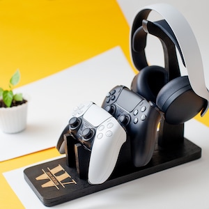 May include: A black wooden stand with a white and black gaming headset, a white and black controller, and a black controller. The stand has the text "III" engraved on it.