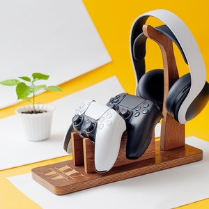 May include: A wooden stand with two black and white video game controllers and a white headset. The stand has the word "WII" engraved on it.