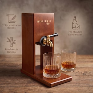 Puede incluir: Un dispensador de licor de madera con un grifo de lat&oacute;n y dos vasos llenos de l&iacute;quido &aacute;mbar. El dispensador tiene el texto "WILLIAM'S Bar" e iconos que indican 12 dise&ntilde;os de personalizaci&oacute;n, bamb&uacute; ecol&oacute;gico y que se adapta a botellas de licor est&aacute;ndar.