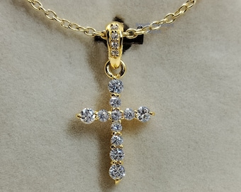 May include: A gold cross pendant necklace with small clear cubic zirconia stones. The cross is set on a delicate gold chain.