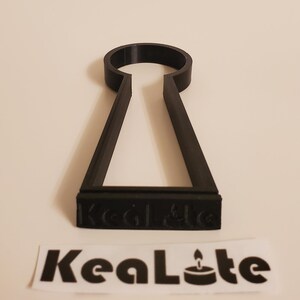 May include: Black plastic key-shaped candle holder with the text "KeaLte" on the bottom.