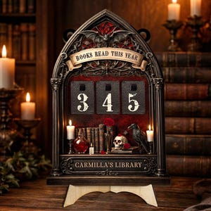 May include: A gothic-style book counter with the text "BOOKS READ THIS YEAR" above the numbers 345. The counter features a decorative frame with a bat and scroll design. The base reads "CARMILLA'S LIBRARY". Candles, books, a skull, and a raven are also visible.