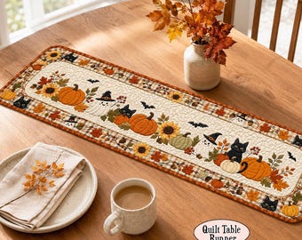 May include: A rectangular quilted table runner featuring a festive autumn and Halloween theme with orange pumpkins, sunflowers, black cats, ghosts wearing witch hats, and small bats on a cream background, bordered by a brown and tan plaid fabric.