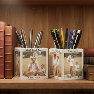 May include: Two white pen holders with family photos and the text "Best Dad Ever" and "Love you". One says "Est. 2014" and the other says "Noah & Lucy". The holders are filled with pens and pencils.