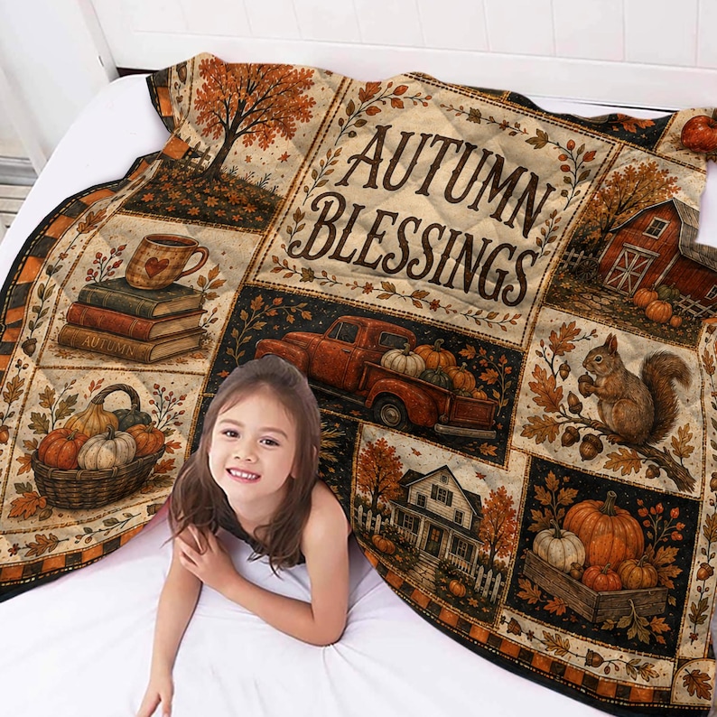 May include: A quilted throw blanket featuring a patchwork design with autumn-themed illustrations including a red truck, pumpkins, a squirrel, a house, and books. The text AUTUMN BLESSINGS is printed in the center in a dark brown serif font.