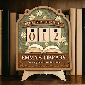 May include: Wooden library sign with the text "BOOKS READ THIS YEAR" and "EMMA'S LIBRARY". The sign displays the number "012" and is decorated with daisies and an open book. It is displayed on a wooden stand.