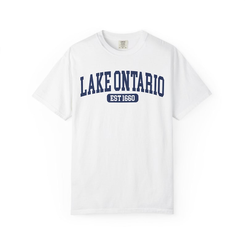 May include: A white short-sleeve crew neck t-shirt featuring the dark blue text LAKE ONTARIO in an arched collegiate font, with the text EST 1660 centered below it inside a dark blue rounded rectangular border on the chest area.