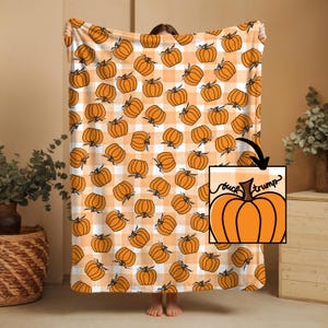 May include: A large orange and white plaid blanket with repeating orange pumpkin illustrations. A small inset shows an orange pumpkin with the words "buck trump".