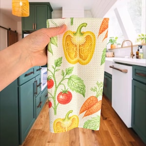 May include: A white waffle-weave kitchen towel featuring a repeating pattern of colorful vegetables including yellow bell peppers, red tomatoes on vines, and orange carrots, with the text "fuck trump" integrated into the vegetable illustrations.
