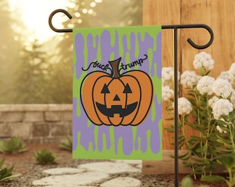 May include: A Halloween garden flag featuring a jack-o'-lantern with the text "fuck trump" in black script. The pumpkin is orange with a black face, set against a green and purple background. The flag is displayed outdoors.