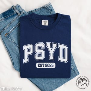 May include: A navy blue t-shirt with white text that reads "PSYD EST 2025".