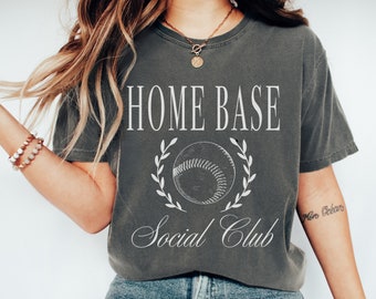 May include: A gray t-shirt with the text "HOME BASE Social Club" and a white baseball graphic with a laurel wreath.