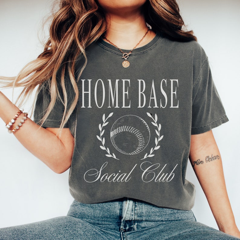 May include: A gray t-shirt with the text "HOME BASE Social Club" and a white baseball graphic with a laurel wreath.