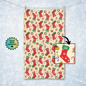 May include: A beige Christmas-themed towel with a repeating pattern of red stockings, gingerbread men, candy canes, and green wreaths. One stocking has the text "FUCK TRUMP". The towel is hanging from a clothesline.