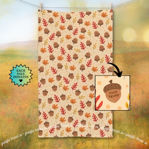 May include: A beige towel with a repeating pattern of acorns and leaves in autumn colors. The acorns have the text "FUCK TRUMP" on them. The towel is hanging on a clothesline.