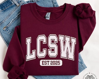 May include: Maroon sweatshirt with white text that reads "LCSW EST 2025".